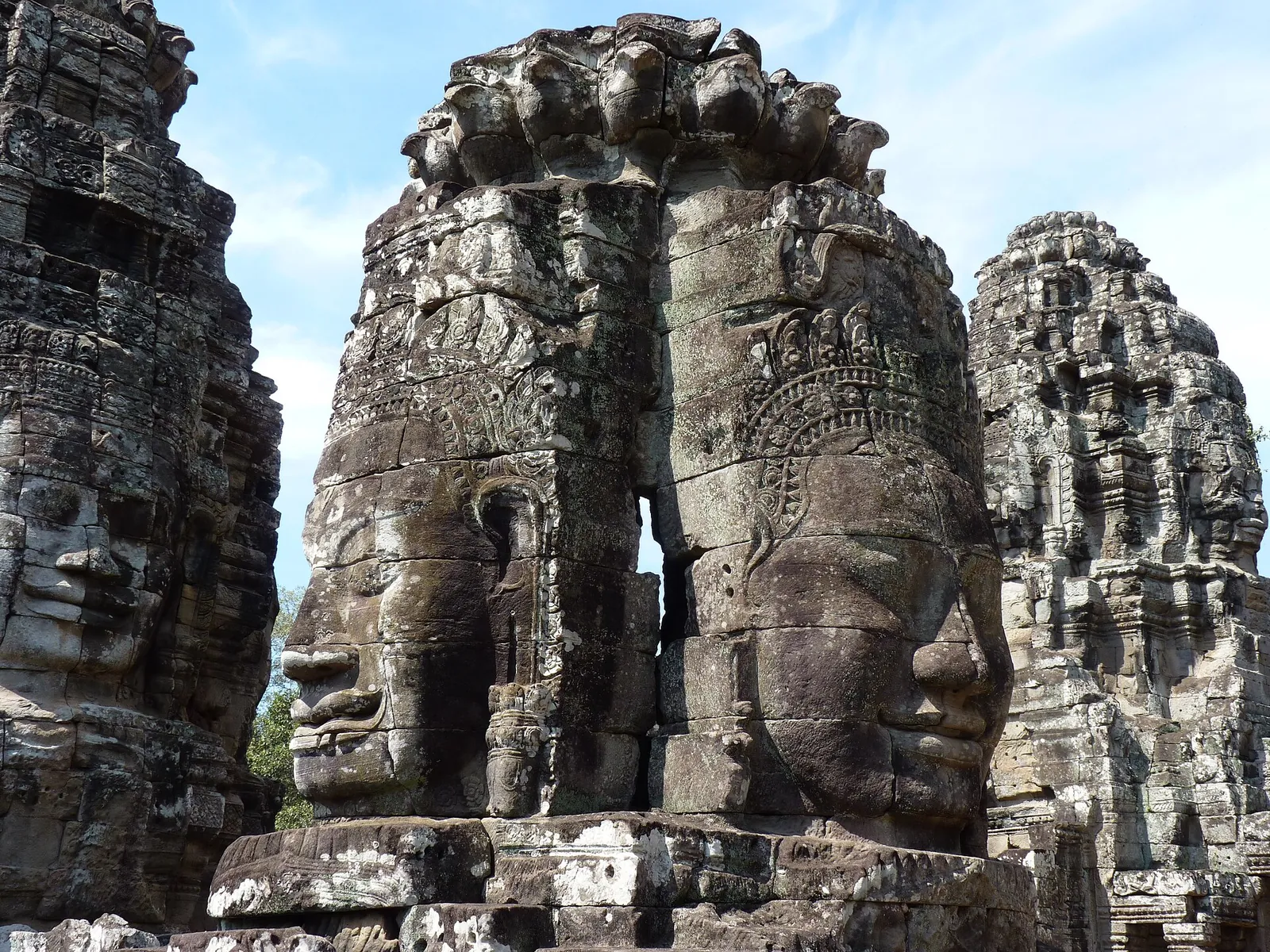 Stone faces on the towers of the Bayon under a blue sky