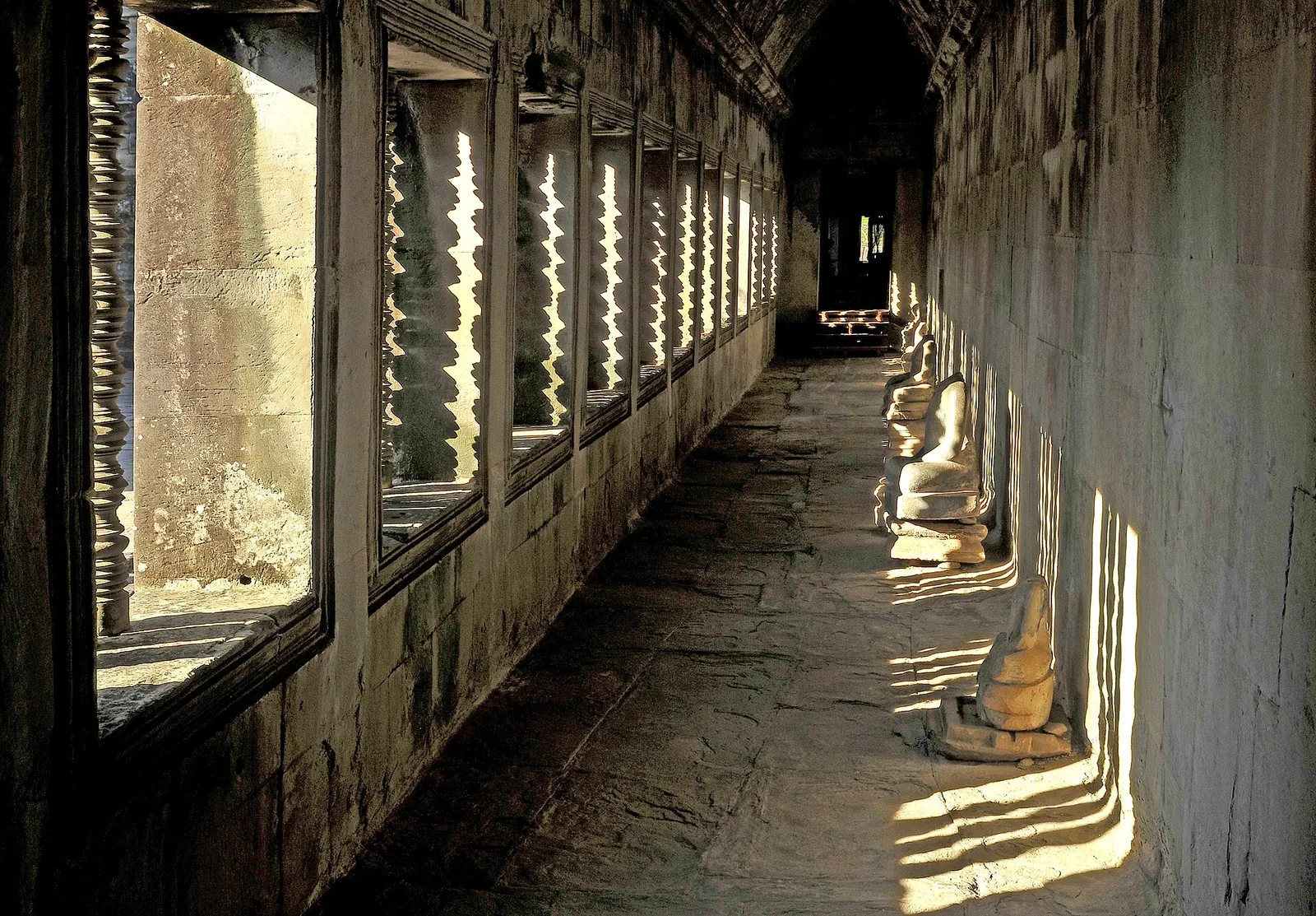 Sluneční světlo mezi kamennými sloupy galerie Angkor Vatu