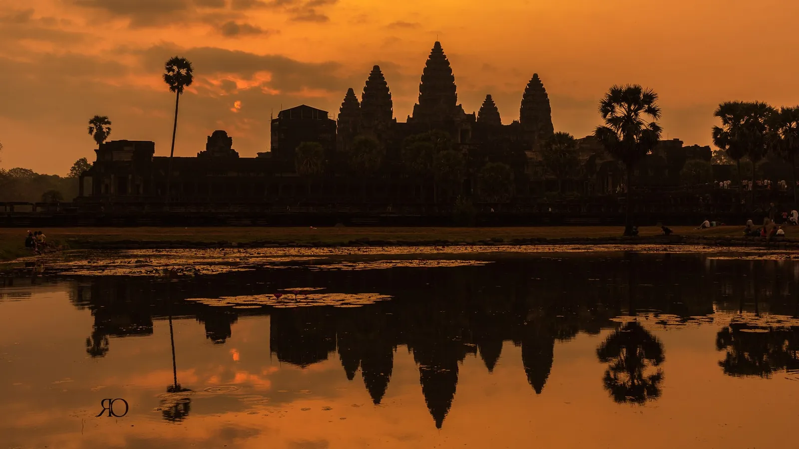 Angkor Wat silhouetted against an orange sunrise and reflected in the pond