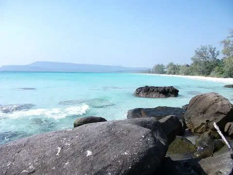 Světlý písek, tyrkysové moře a pobřežní skály na Sok San Beach na Koh Rongu
