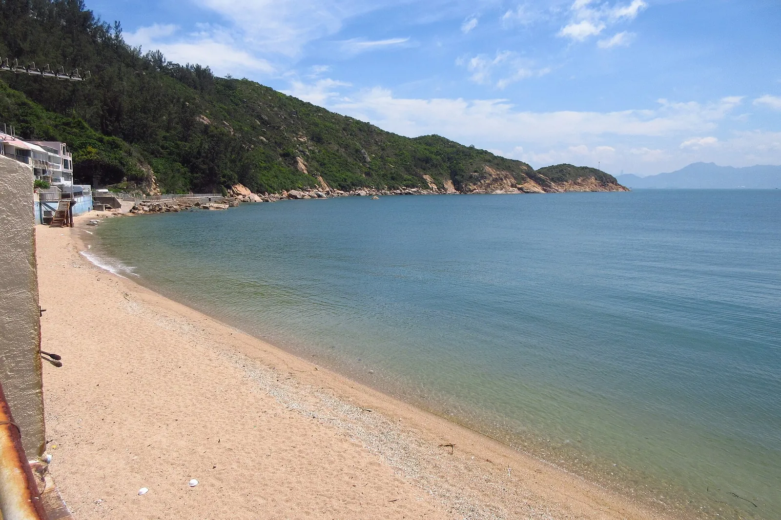 Playa de Tung Wan con arena, mar y el promontorio verde