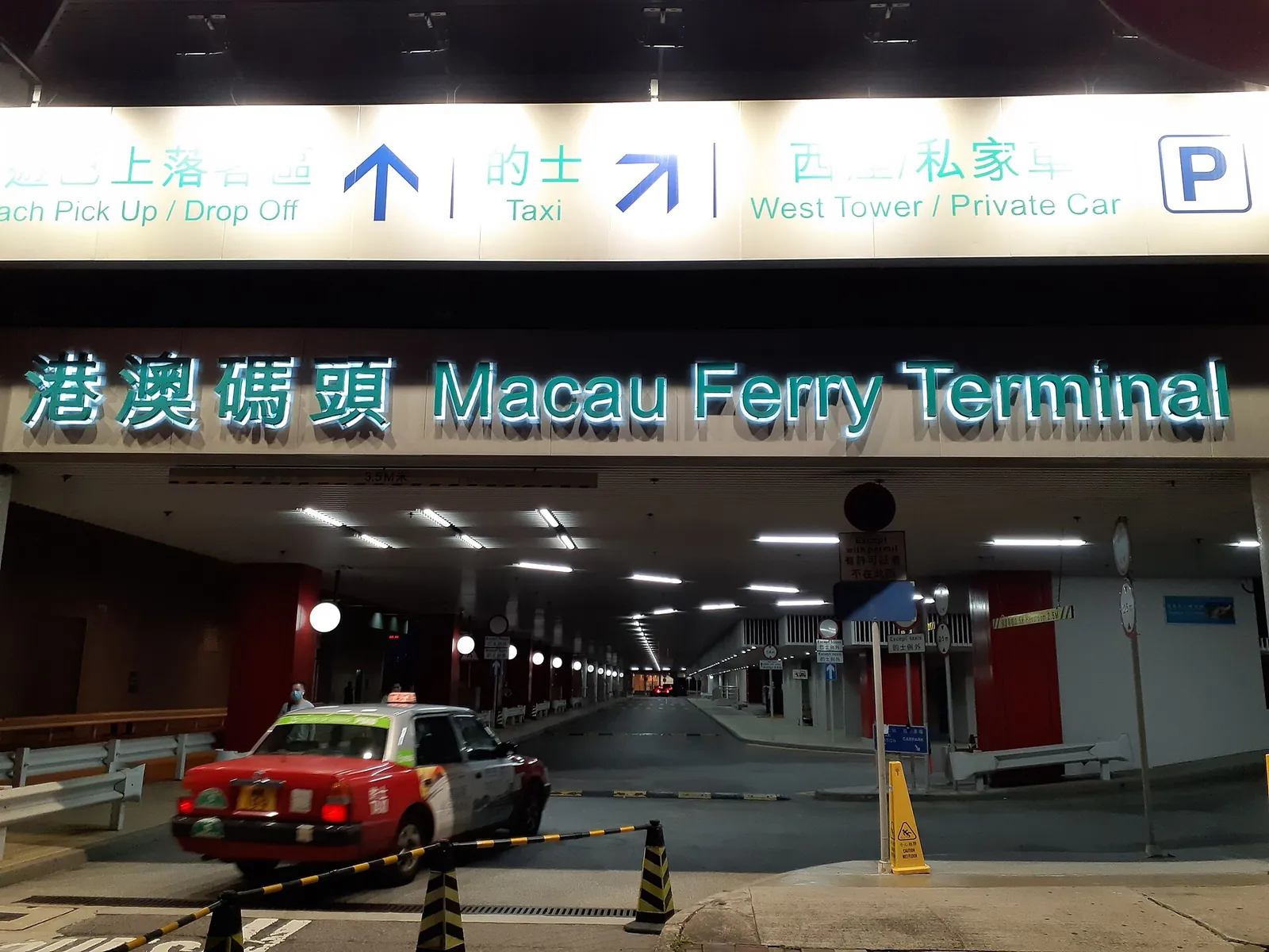 Osvětlený nápis Macau Ferry Terminal nad vjezdem pro vozidla v Sheung Wanu