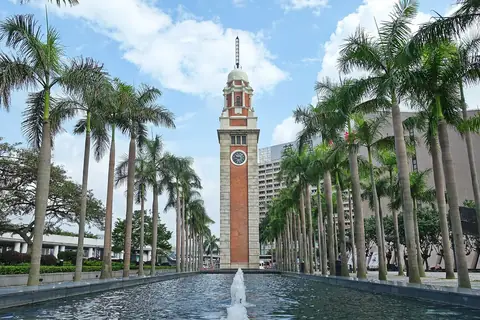Hodinová věž bývalé železnice Kowloon–Canton mezi palmami
