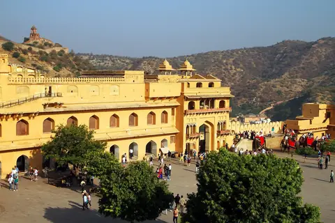 Los muros amarillos del palacio y el patio del fuerte de Amber bajo colinas rocosas cerca de Jaipur, bajo un cielo azul despejado
