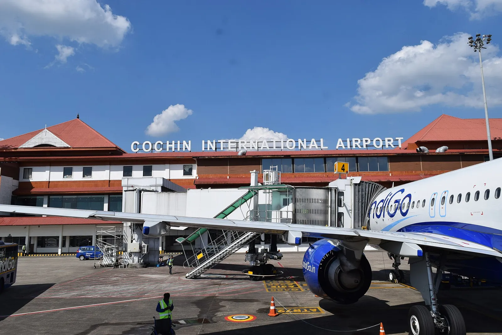 Terminál mezinárodního letiště Cochin s červenými taškovými střechami při pohledu z odbavovací plochy vedle letadla IndiGo
