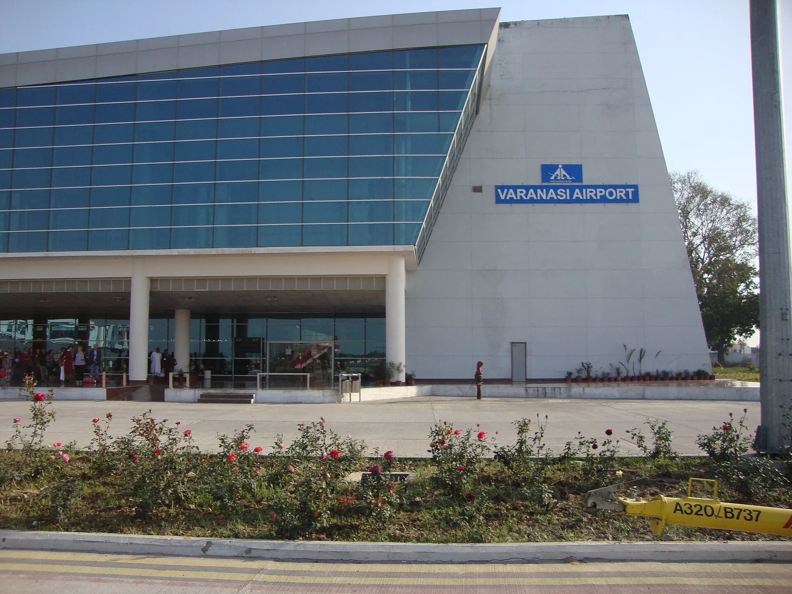 Prosklená budova terminálu s nápisem Varanasi Airport za záhonem s květinami