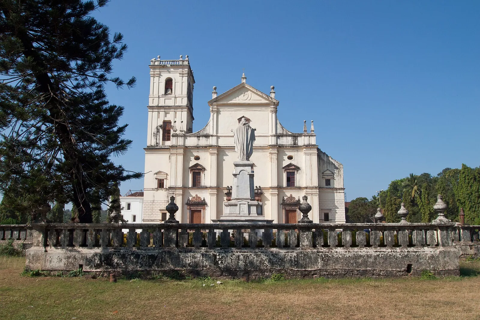Bílá katedrála Sé v Old Goa se sochou před ní pod modrou oblohou