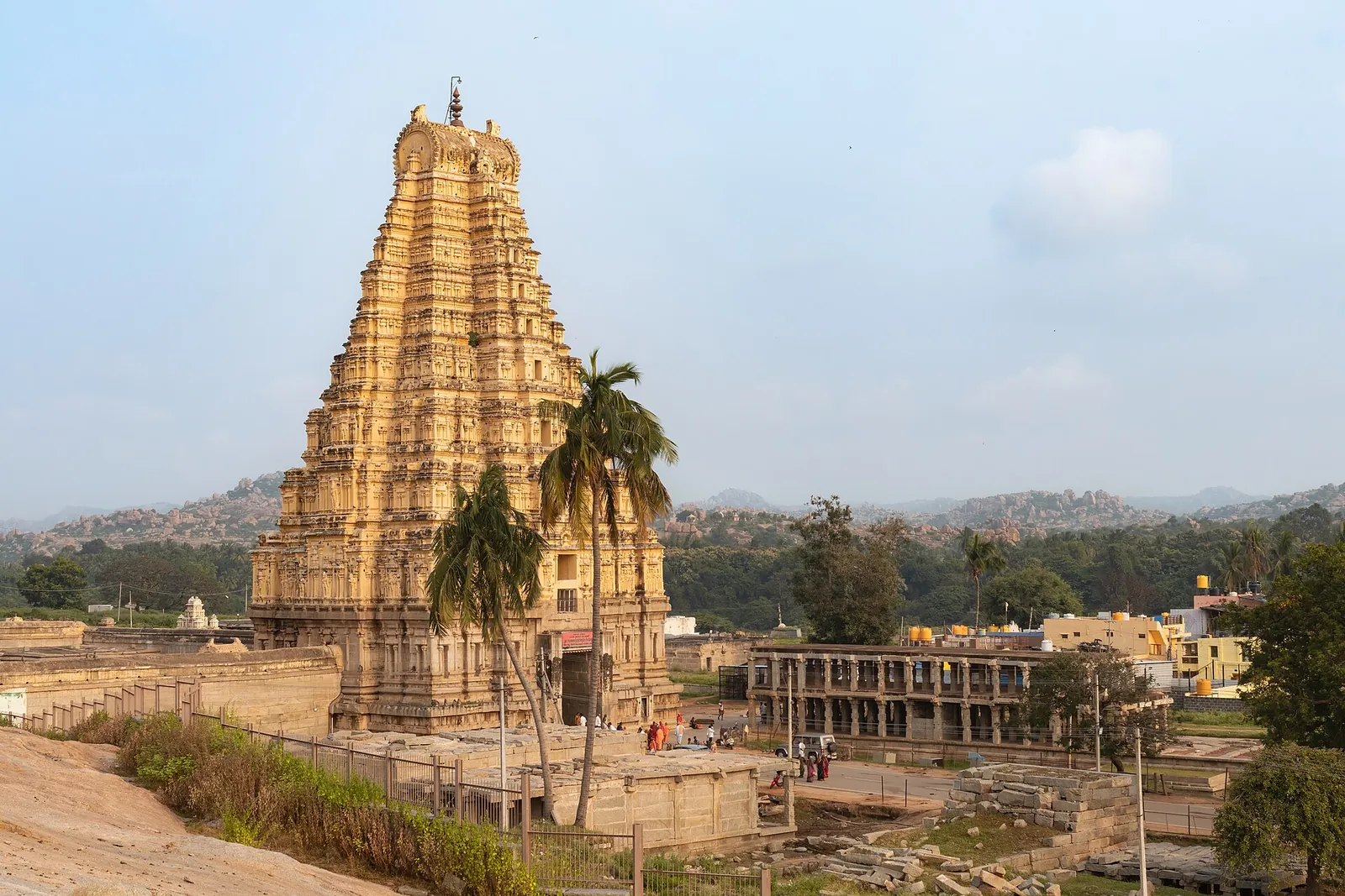 Înaltul gopuram estic al templului Virupaksha, cu palmieri și dealurile de bolovani din Hampi
