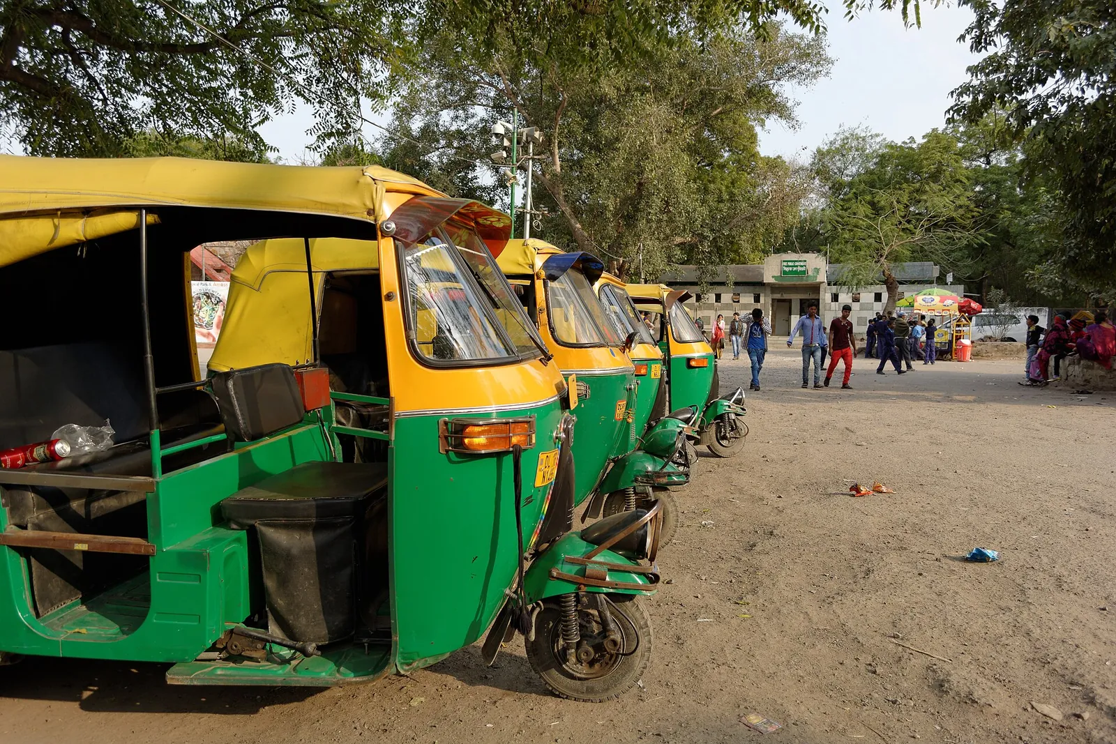 Grønne og gule autorickshaws parkeret på række uden for Purana Qila i Delhi