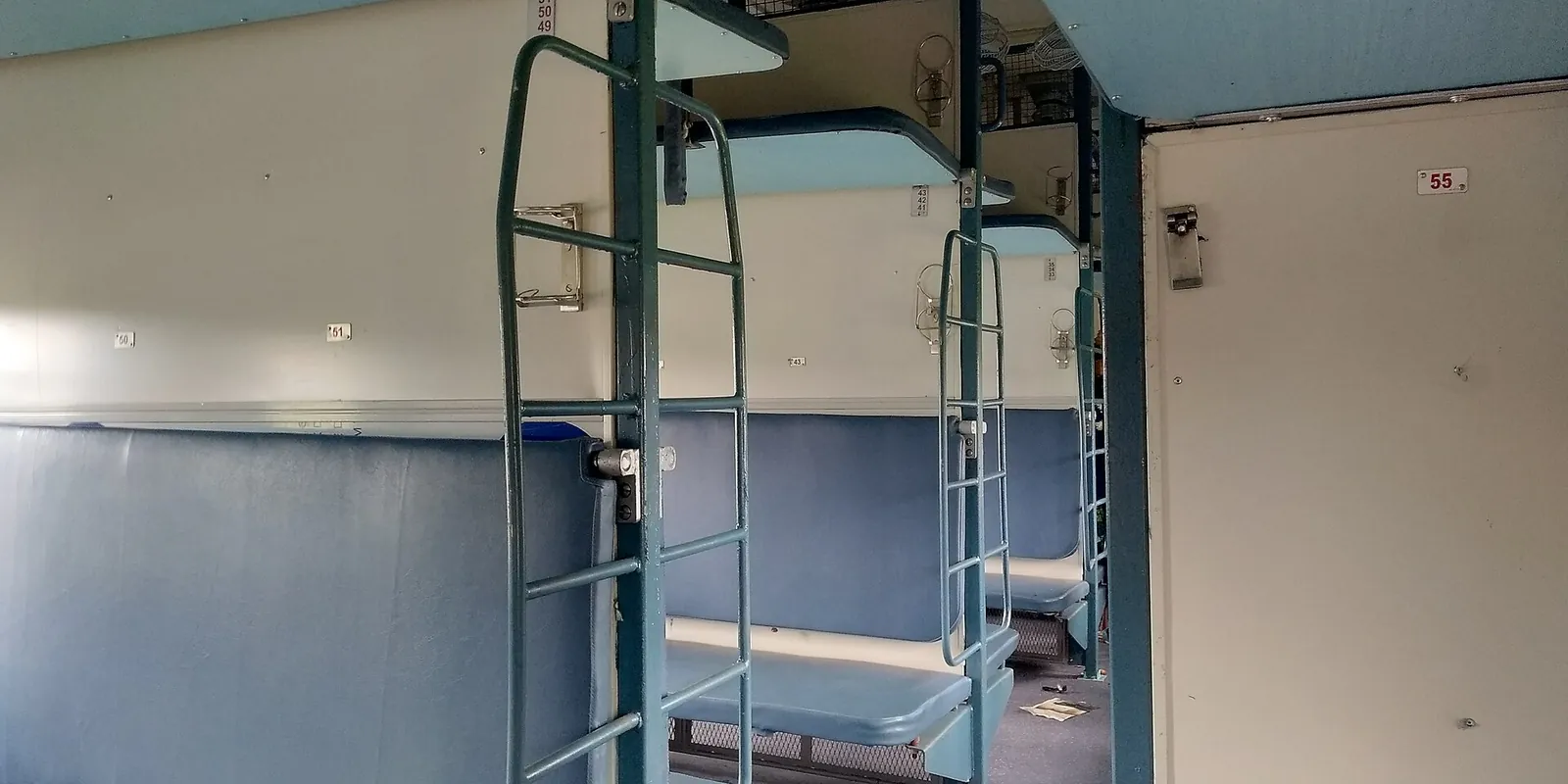 Blå køjer med metalstiger inde i en sleeper-vogn hos Indian Railways