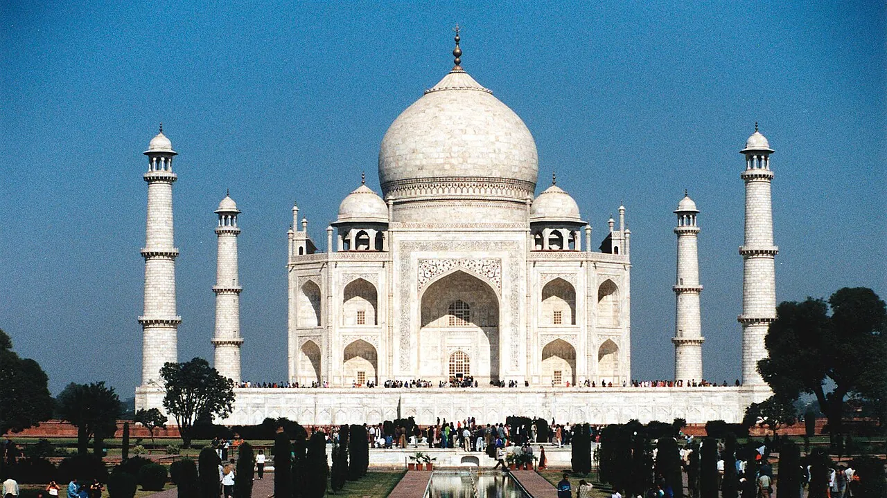 The white marble Taj Mahal and its minarets seen across the garden