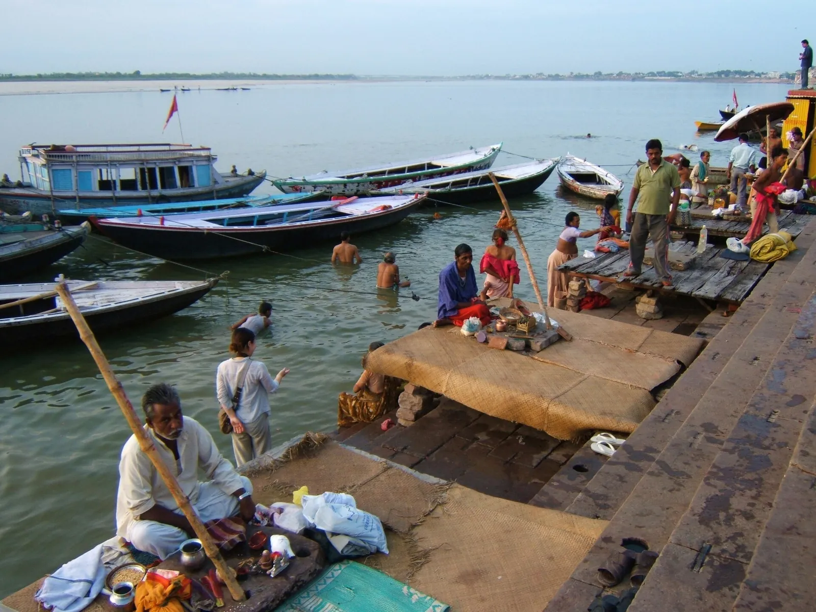 Pilgrims bathing from the ghats of Varanasi beside moored wooden boats on the Ganges