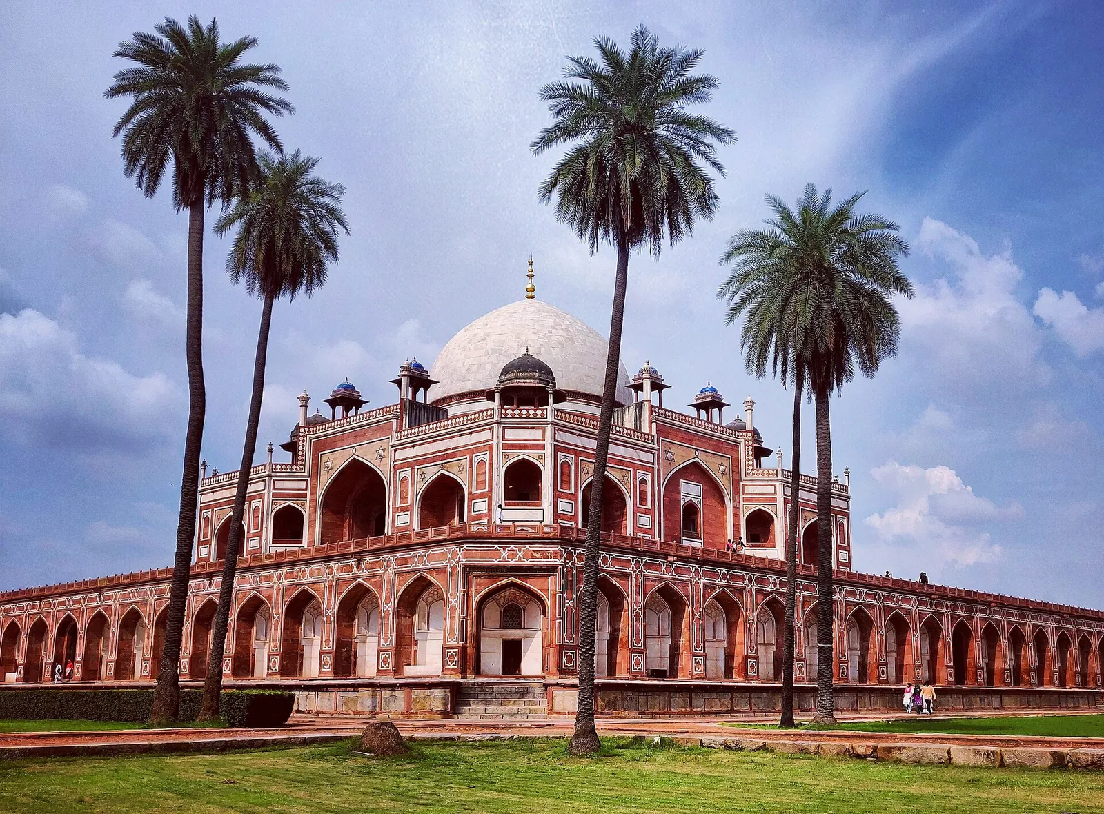 Humayun's Tomb in red sandstone framed by tall palm trees