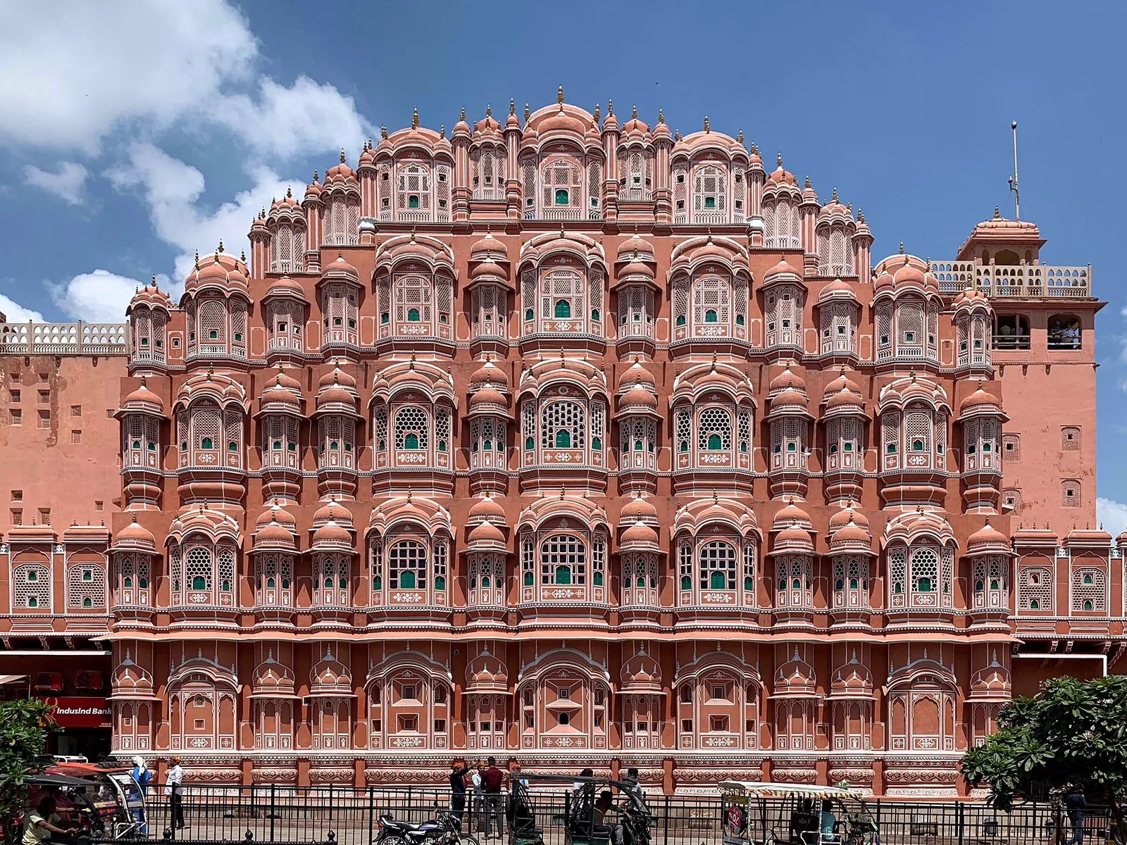 Východní fasáda paláce Hawa Mahal z růžového pískovce v Džajpuru s řadami malých mřížovaných oken pod modrou oblohou