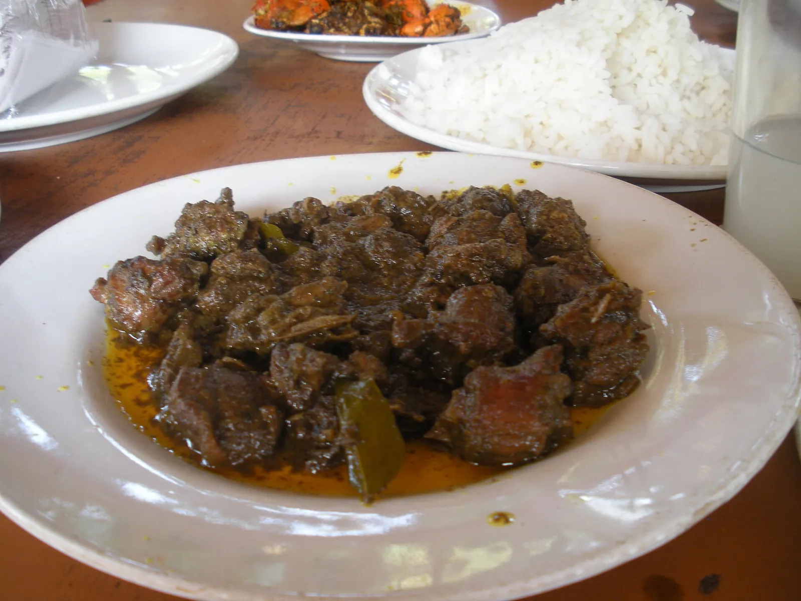 A plate of dark Kerala-style duck curry beside a bowl of white rice