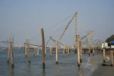 Redes de pesca chinas sobre armazones de teca y bambú en el agua frente a la playa de Fort Kochi