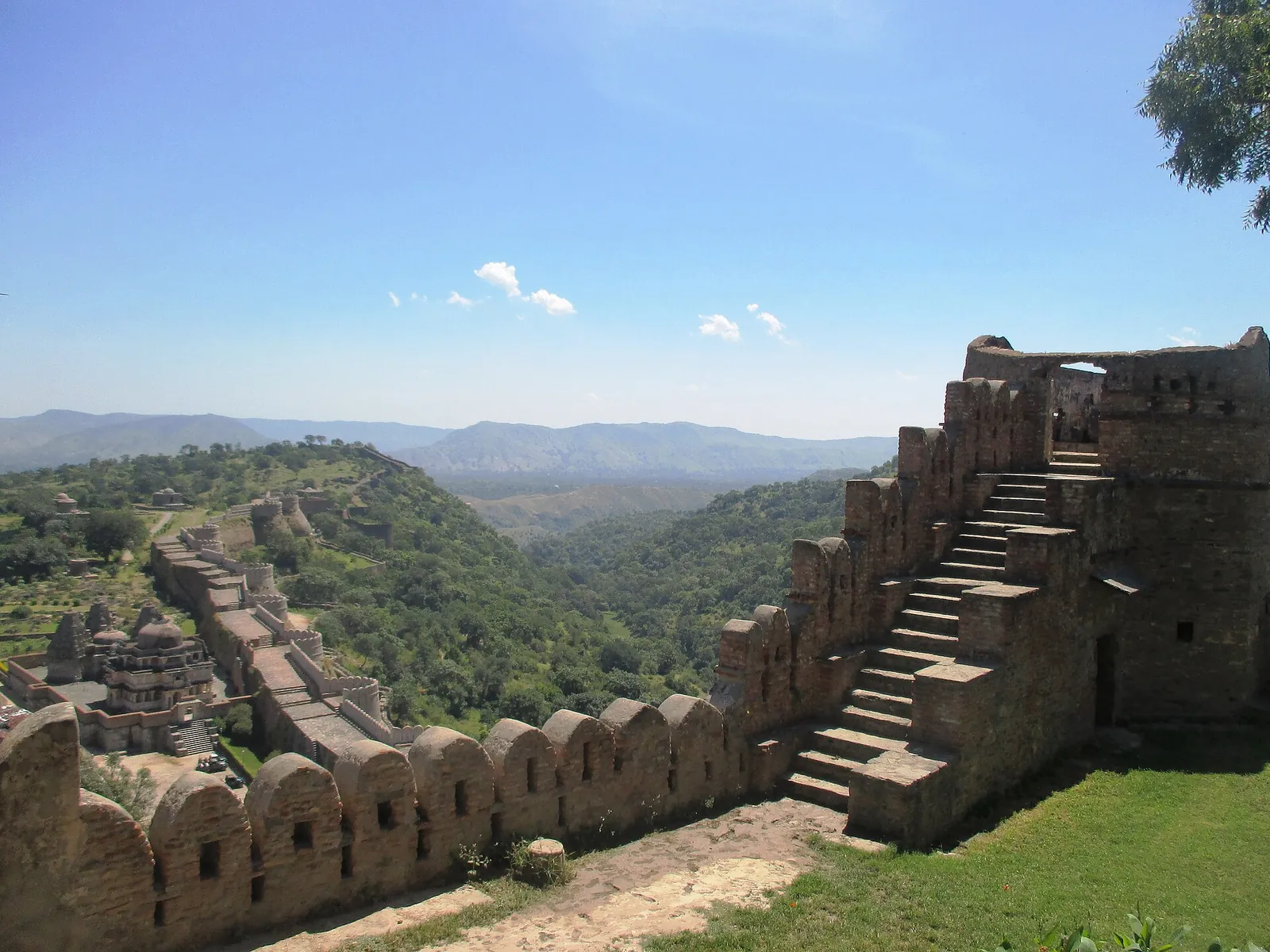 Zidurile fortului Kumbhalgarh întinzându-se peste dealuri verzi, văzute de la palat