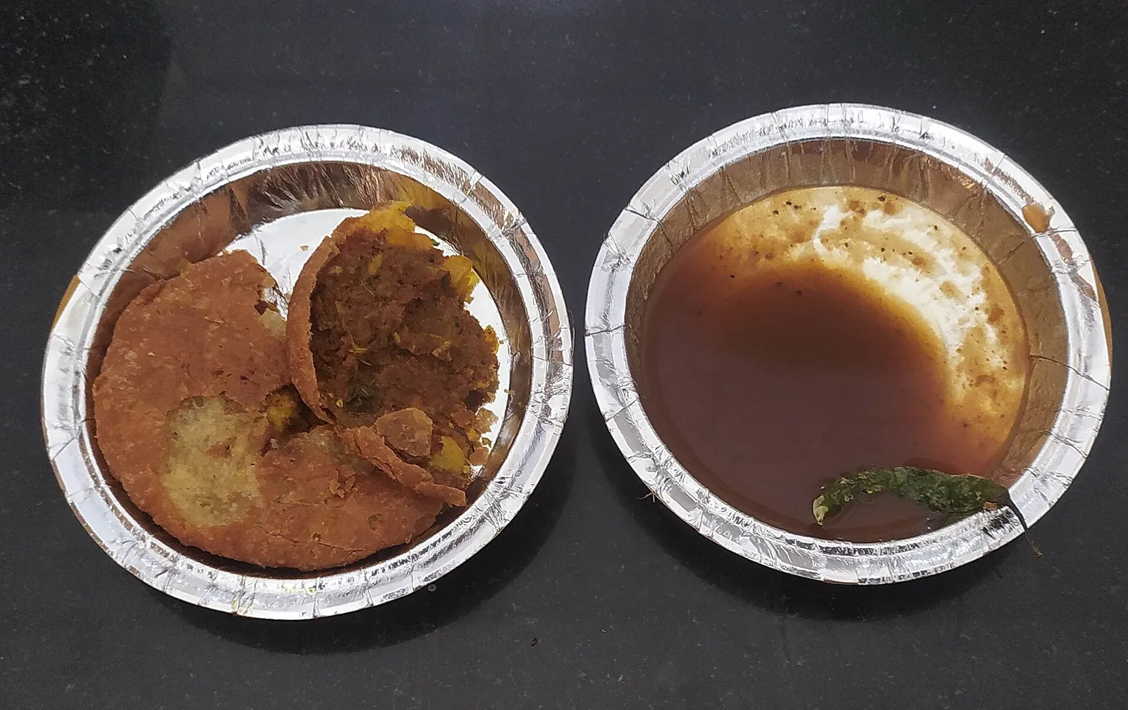 Un pyaaz kachori rupt în două, lângă un castron cu chutney de tamarind