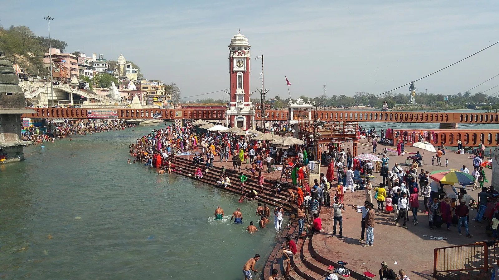 Das Ghat Har Ki Pauri in Haridwar mit seinem Uhrturm, Pilgern auf den Stufen und Badenden im Ganga