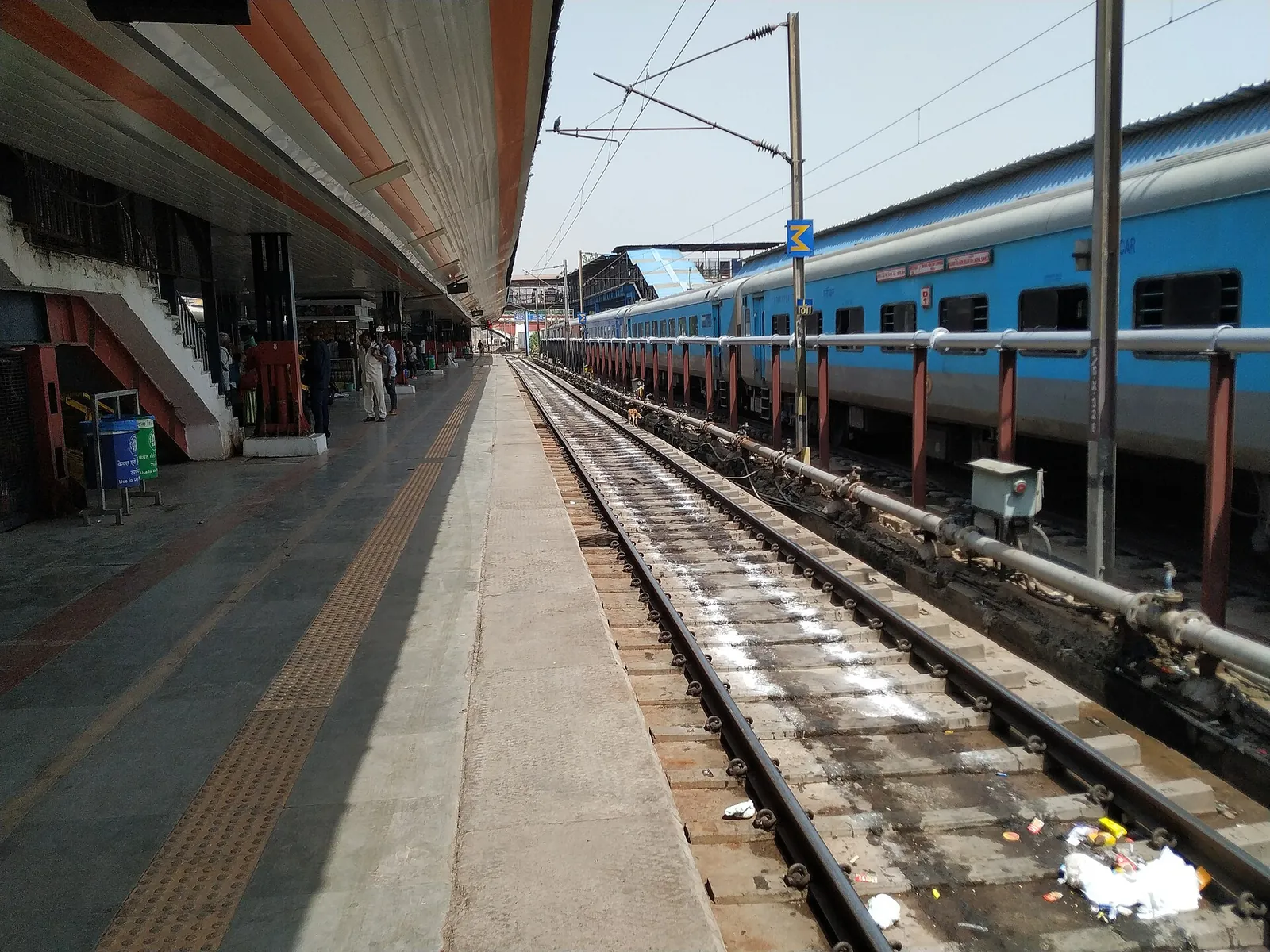 A long blue Gomti Express train beside an almost empty platform at New Delhi Railway Station