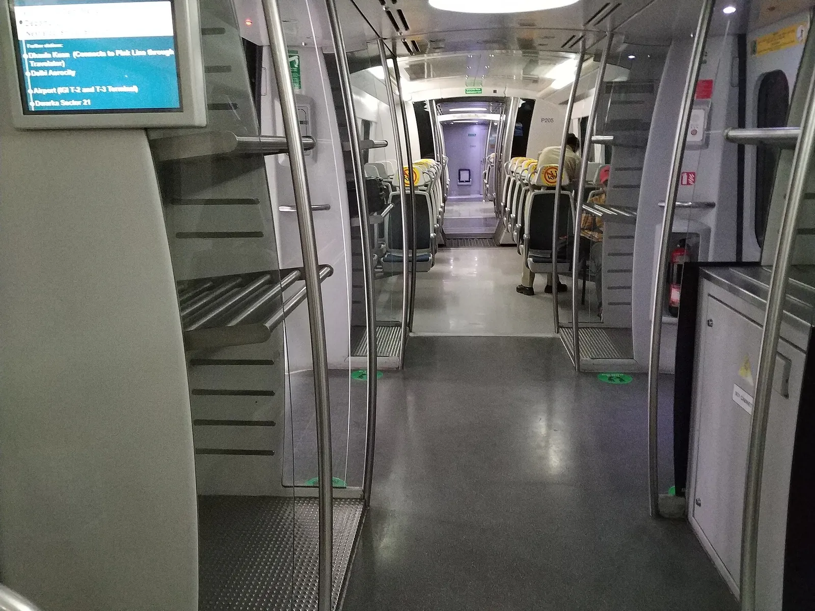 The interior of a Delhi Airport Express metro carriage, with luggage racks by the door and rows of seats beyond