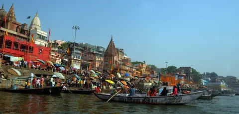 Das Dashashwamedh Ghat in Varanasi mit Tempeln, Sonnenschirmen und Booten auf dem Ganges
