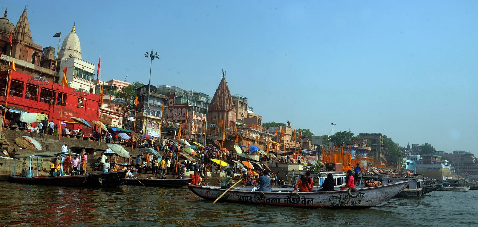 Ghatul Dashashwamedh din Varanasi, cu temple, umbrele și bărci pe Gange