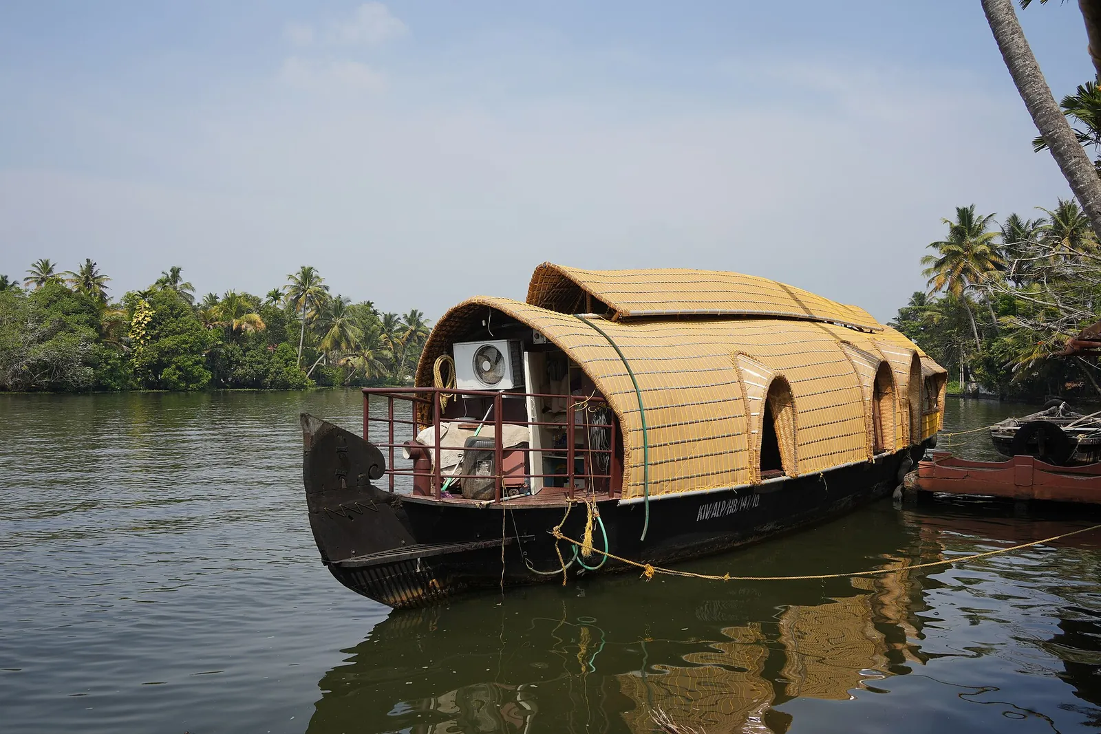 Una casa flotante de Kerala con techo de paja amarrada en los backwaters cerca de Nedumudy, con palmeras a lo largo de la orilla