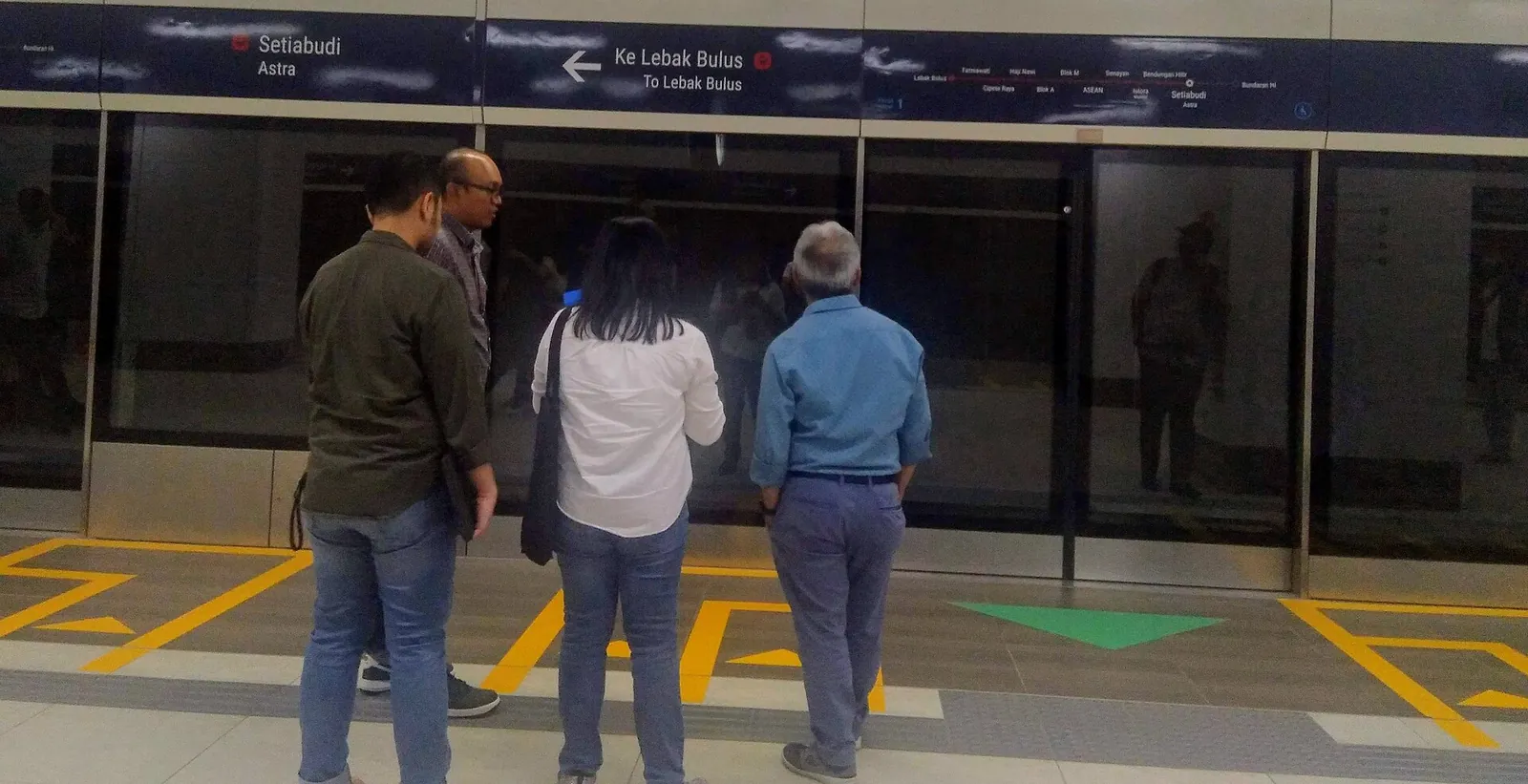 Passengers waiting behind platform screen doors at Setiabudi station on the Jakarta MRT, with yellow tactile paving on the floor