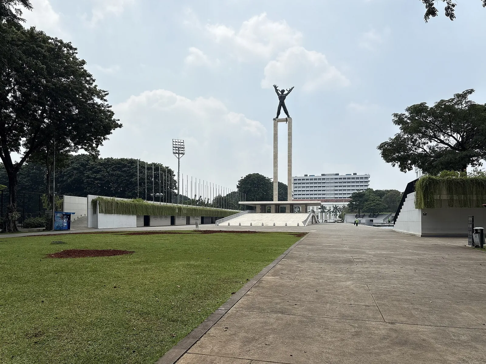 A wide paved walkway across the lawn at Lapangan Banteng in Central Jakarta, leading to the West Irian Liberation Monument