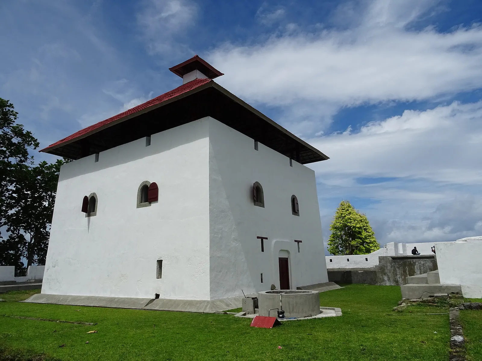 White walls and red roof of Fort Amsterdam's tower under a blue sky at Hila