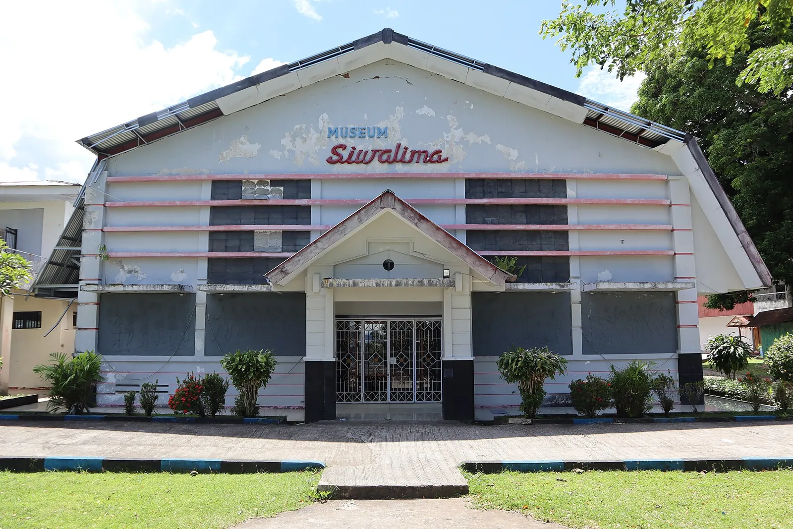 Front of the Siwalima Museum building with its curved roof and the museum name above the entrance