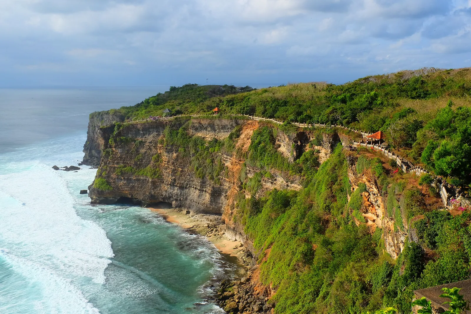 Sheer limestone cliffs above the sea at Pura Luhur Uluwatu, with the temple path along the clifftop