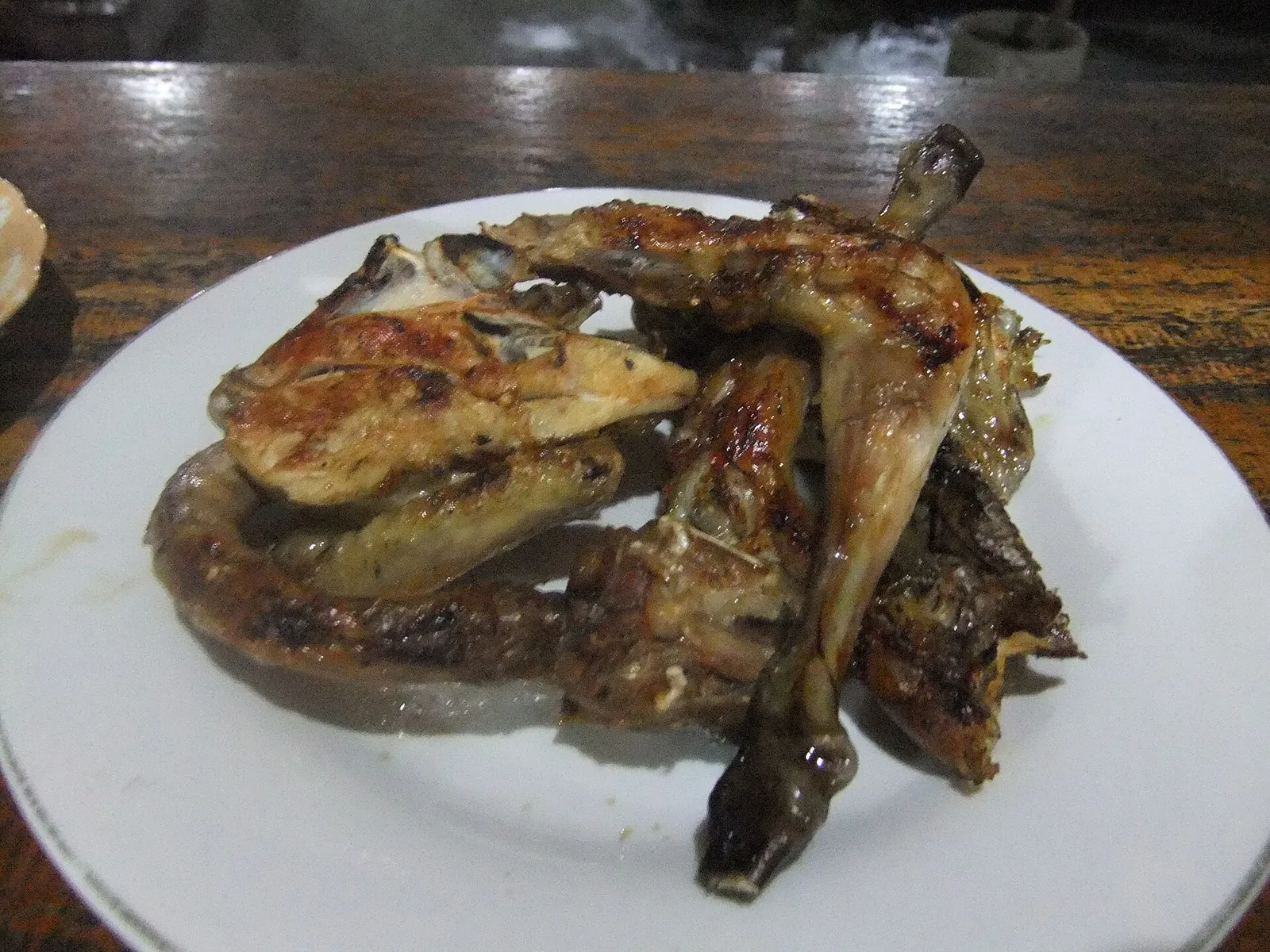 Plate of grilled ayam taliwang, spiced grilled chicken, on a wooden table