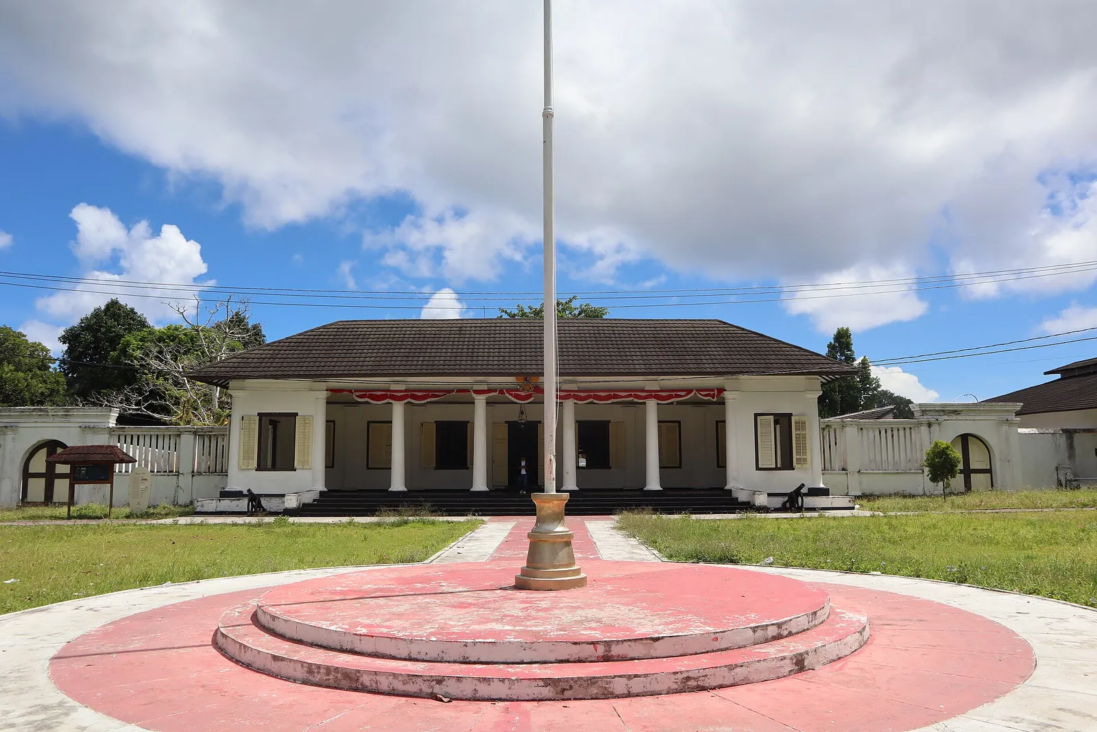 Istana Mini, a white colonial building with a columned front, behind a lawn and flagpole in Banda Neira