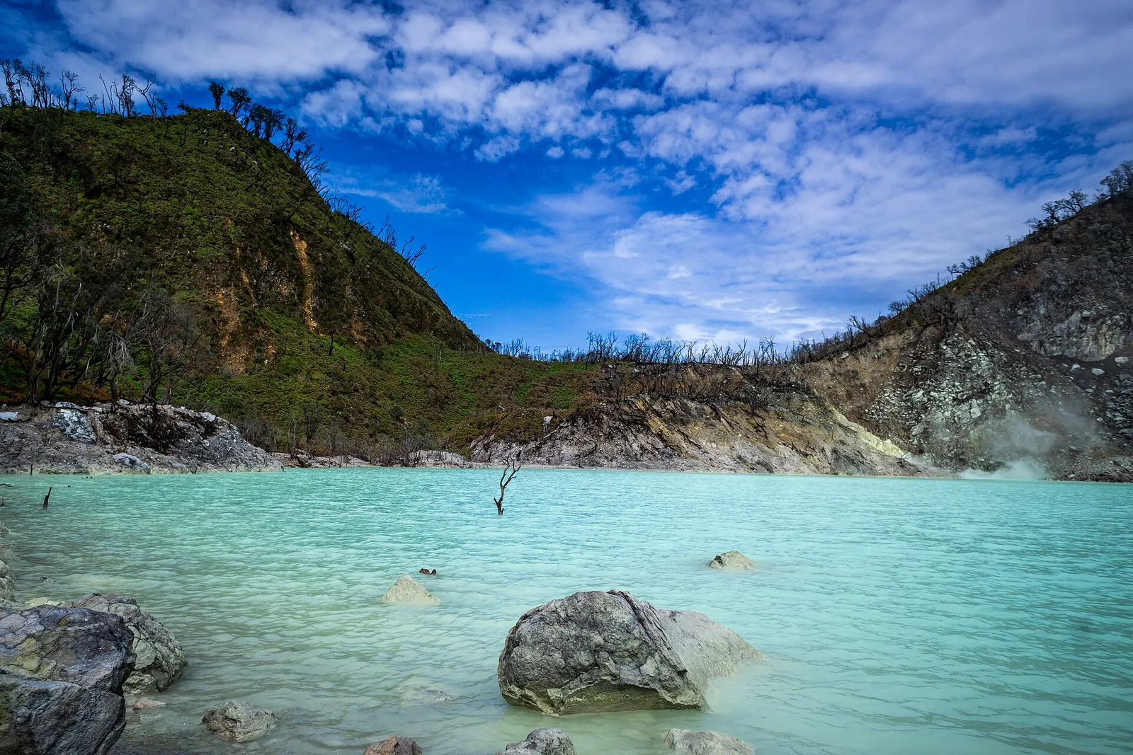 The turquoise crater lake of Kawah Putih on Mount Patuha near Ciwidey, ringed by pale rocky banks and green slopes
