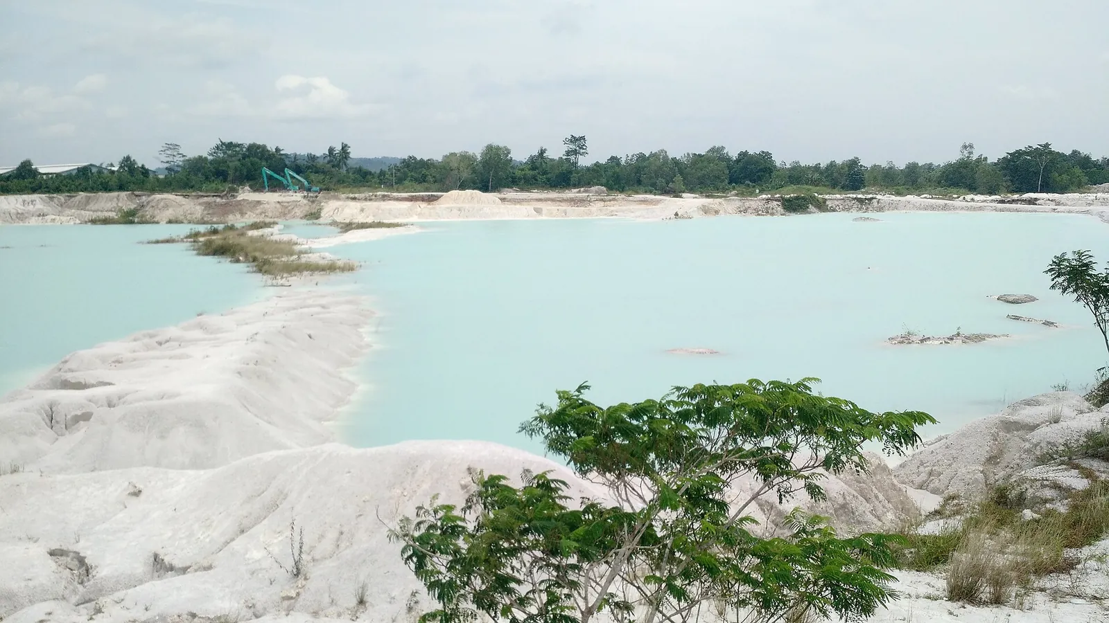 Pale white mining spoil around a milky turquoise lake at Danau Kaolin, Belitung