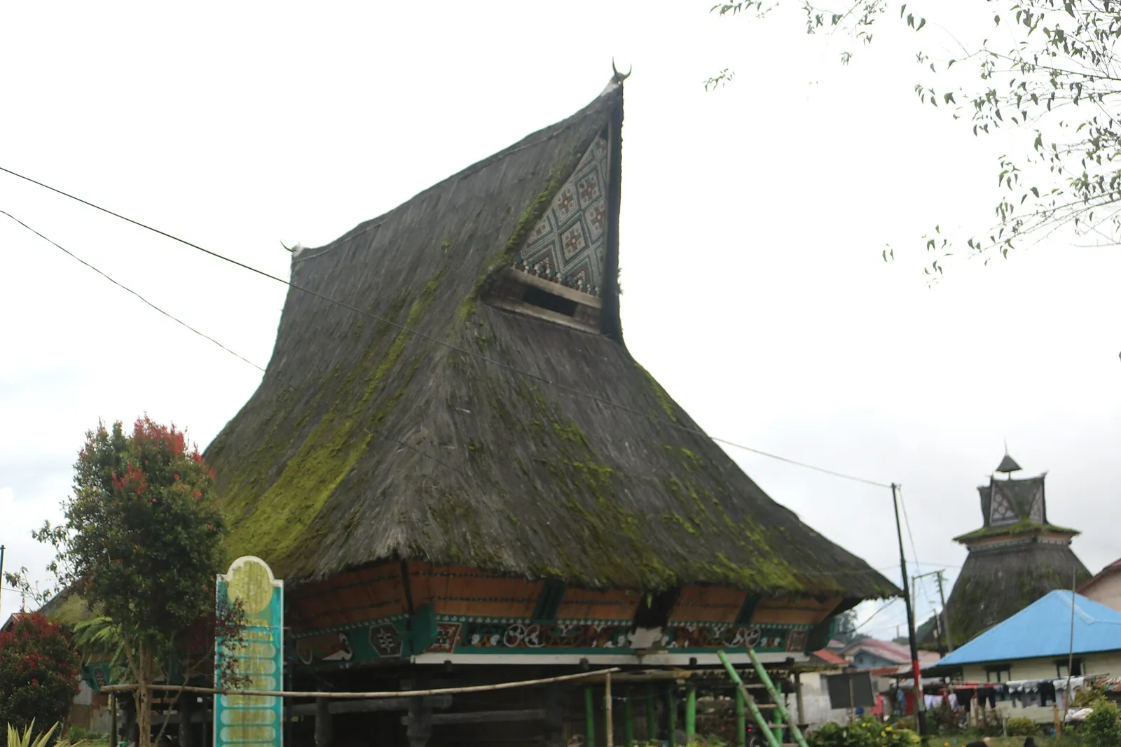 A traditional Karo siwaluh jabu house with a tall, steep thatched roof and horned gable in Lingga village