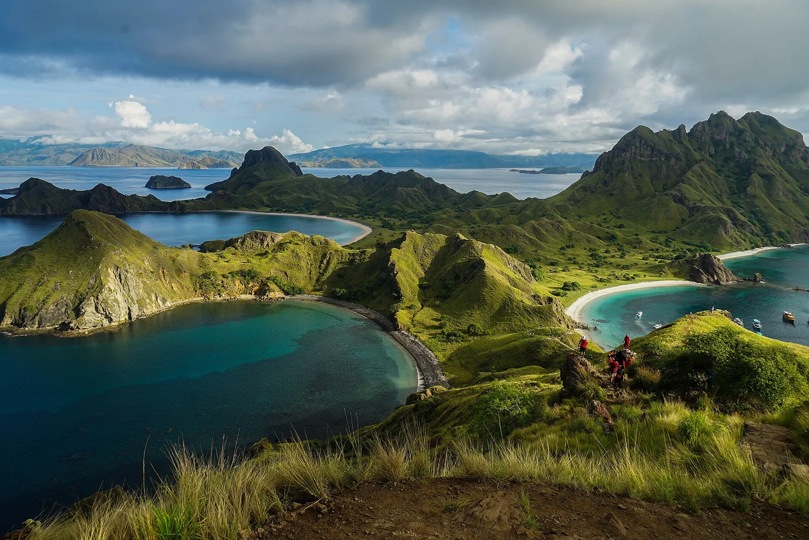 Green grassy ridges and curving bays of Padar Island under cloud