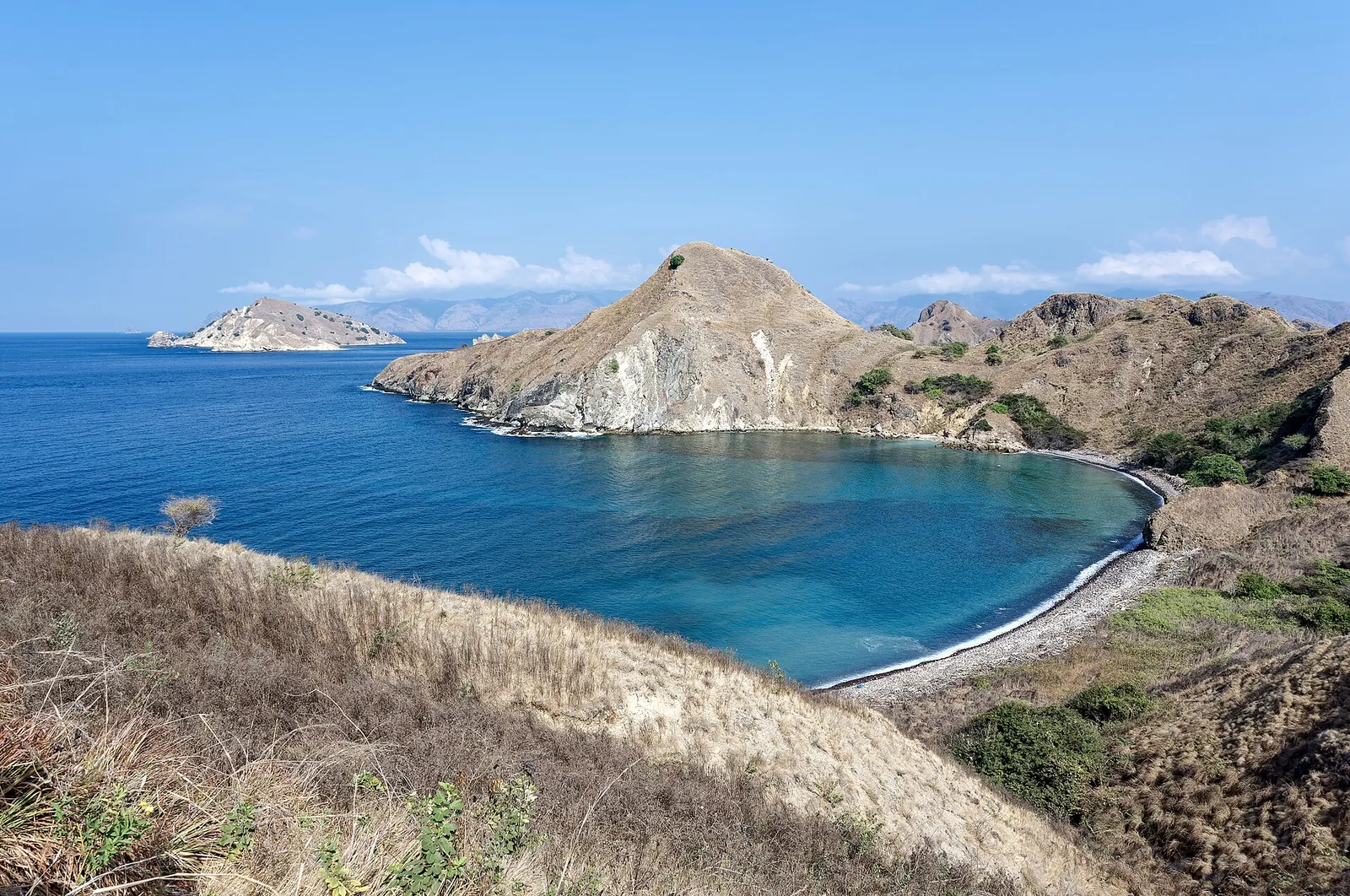 Dry brown hills of Padar Island above a deep blue bay