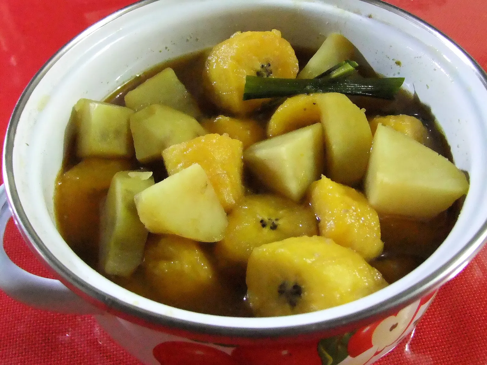 Bowl of kolak with chunks of banana and sweet potato in a palm-sugar syrup