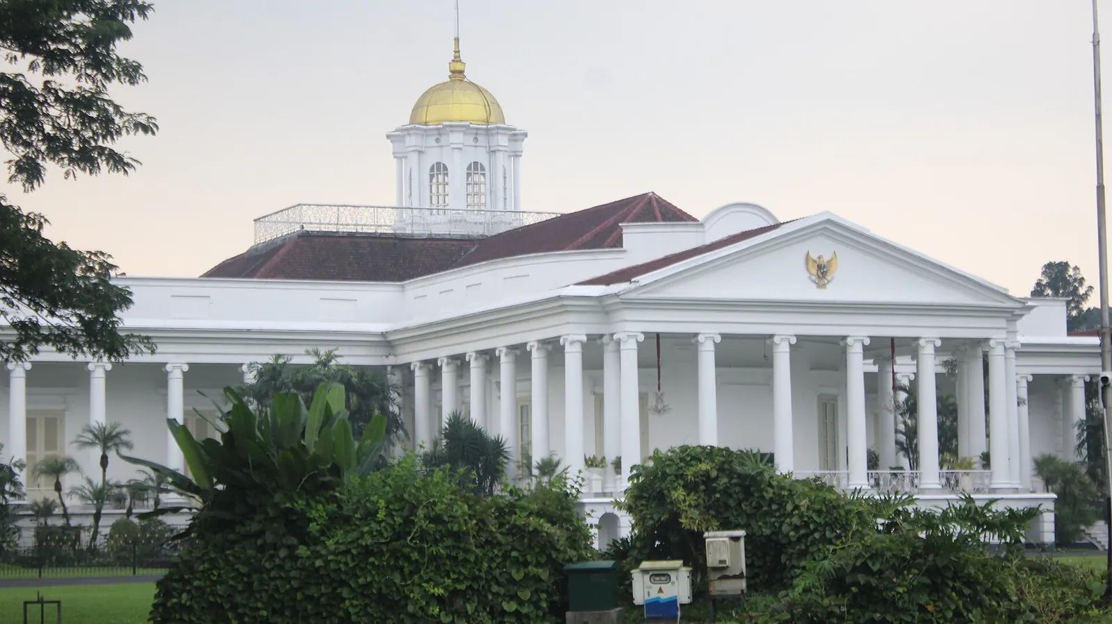 The white colonnaded Bogor Presidential Palace with its domed roof behind palms