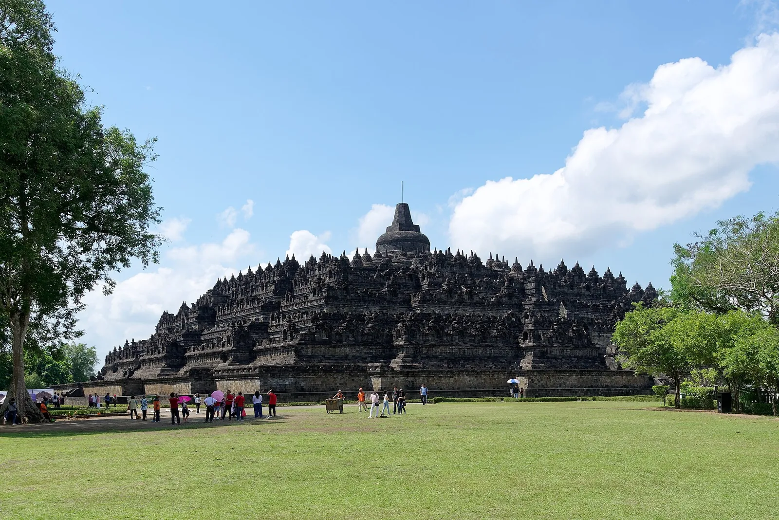 Borobudur temple seen across the lawn of the temple park under a blue sky