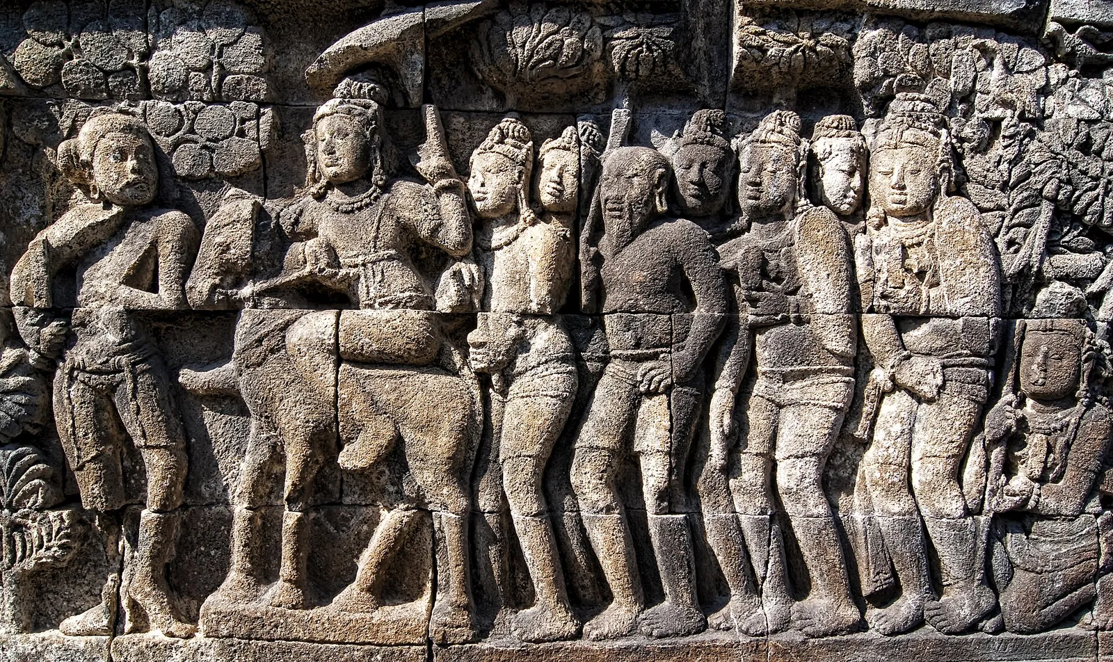 Carved stone relief panel at Borobudur showing a procession of figures