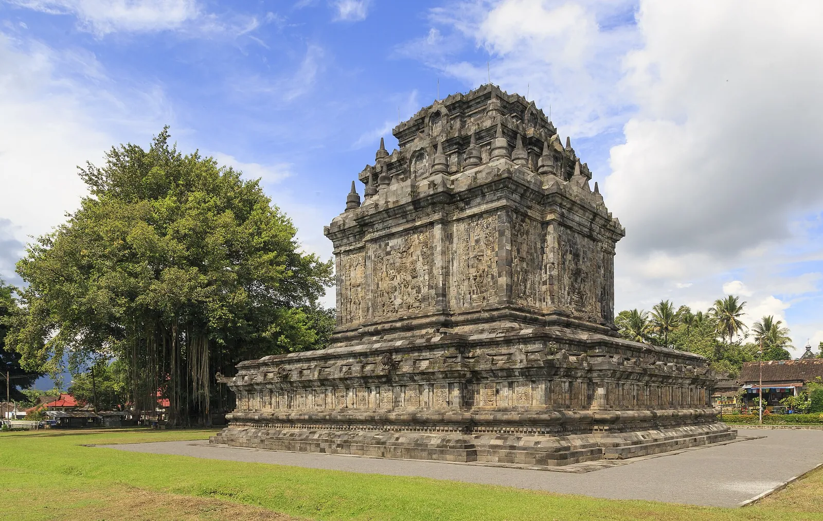 Candi Mendut, a stone Buddhist temple on a grassy lawn with trees