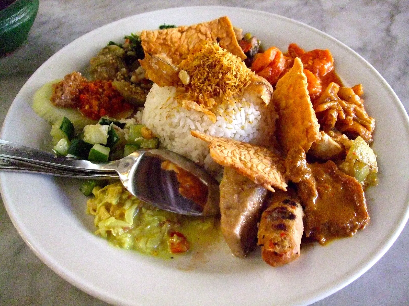 A plate of nasi campur with rice, fried tempeh, vegetables, satay and sambal at Made's Warung in Bali