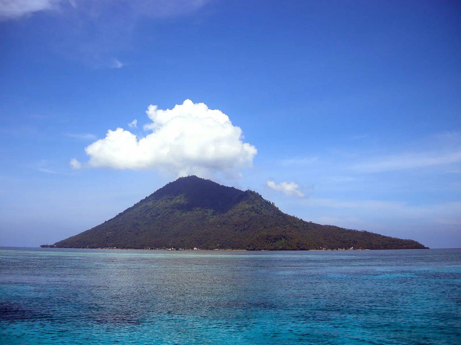 The cone-shaped extinct volcano of Manado Tua rising from turquoise water under a blue sky