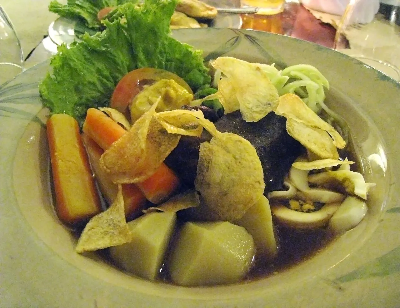 A plate of Selat Solo with braised beef, potato, carrot, lettuce and crisps in a dark sweet gravy