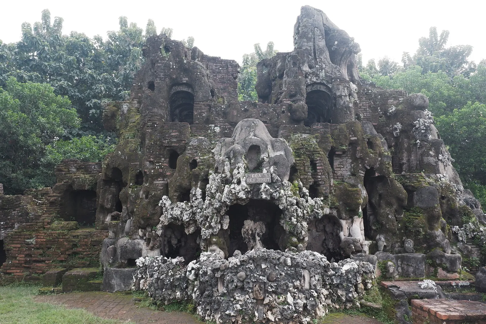 Grey coral-rock grottoes and niches of Taman Sari Gua Sunyaragi among trees in Cirebon