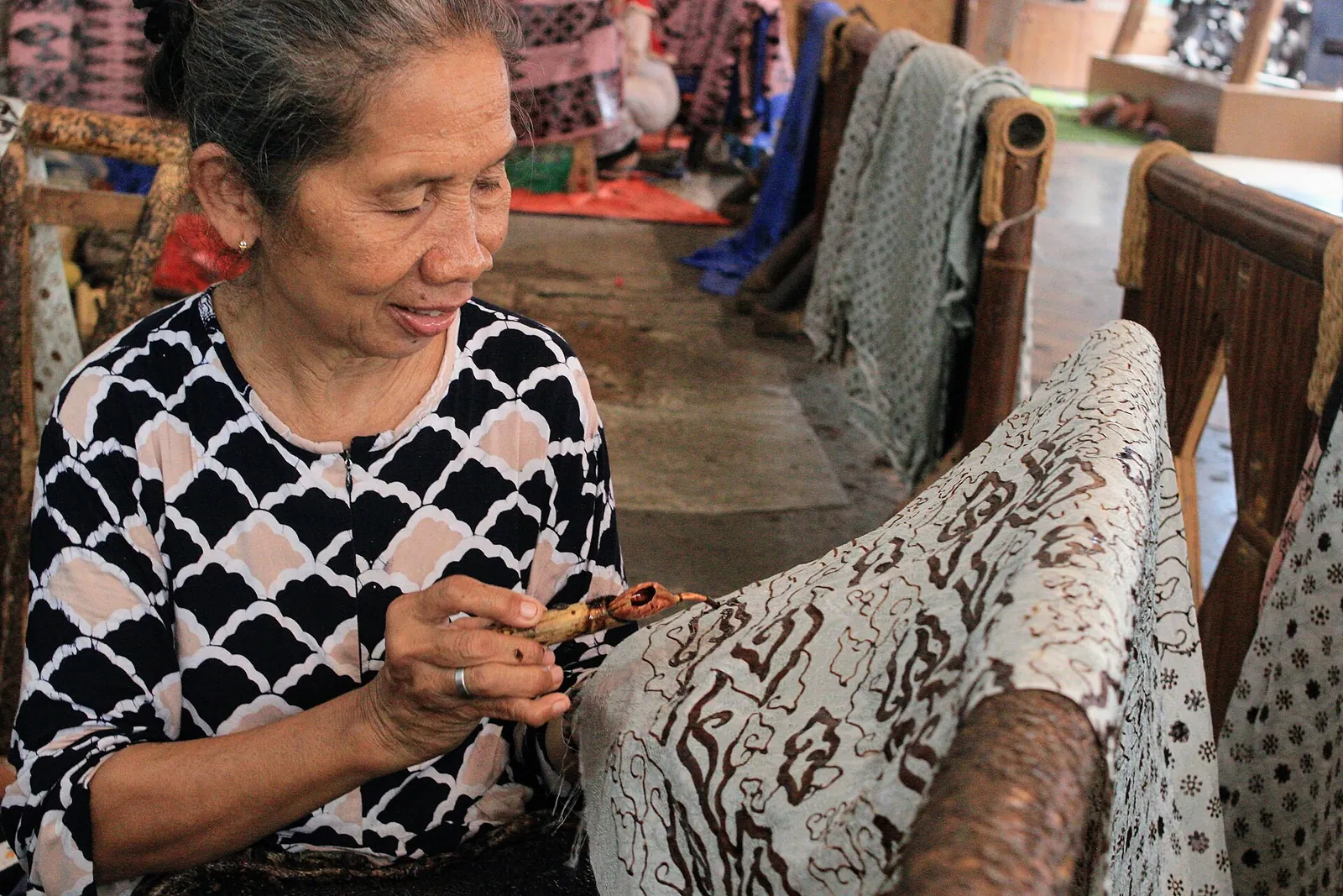 A batik artisan applying hot wax with a canting to hand-drawn batik cloth in Trusmi, Cirebon